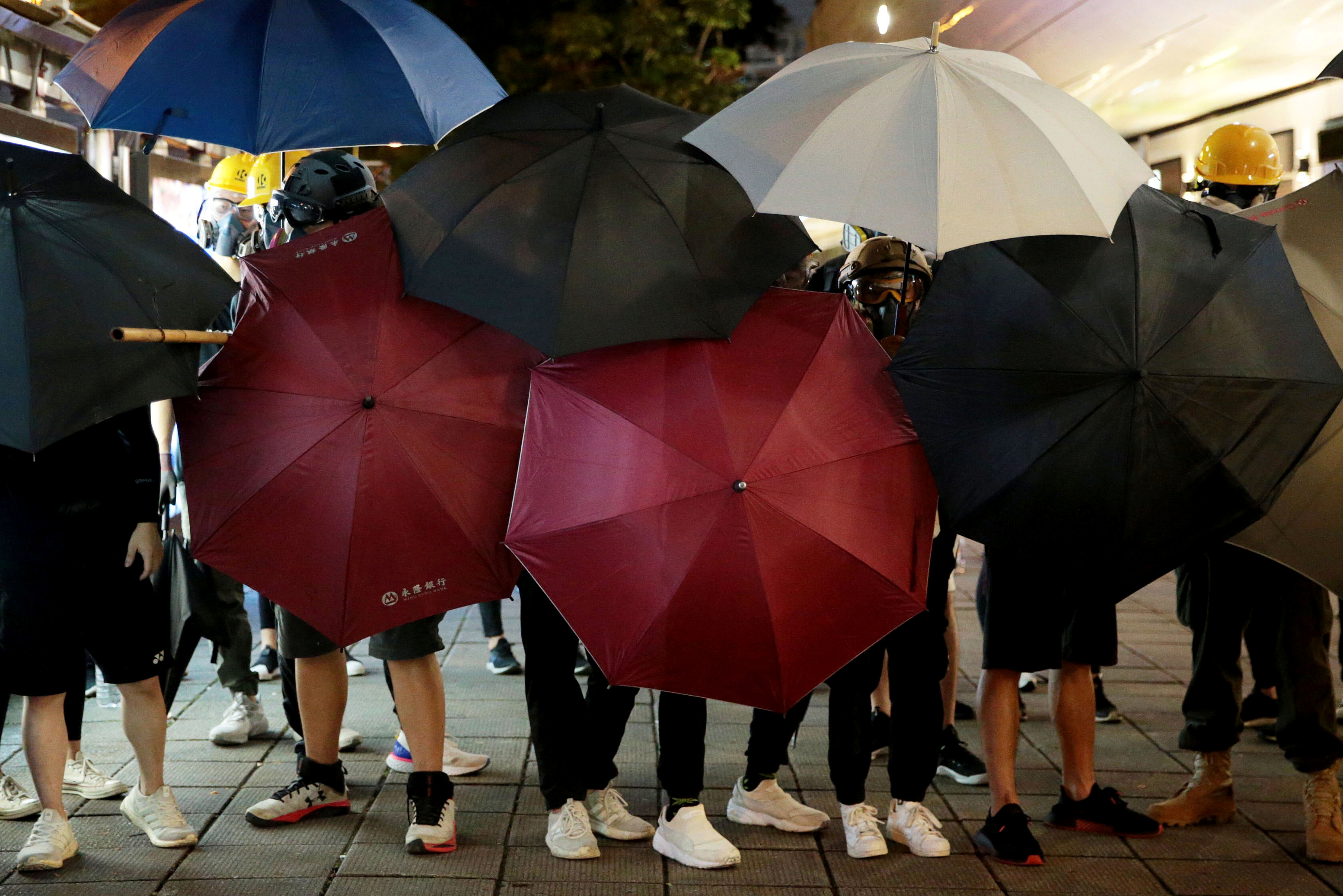 示威者用雨伞遮挡警方拍摄他们的脸部。-路透社-