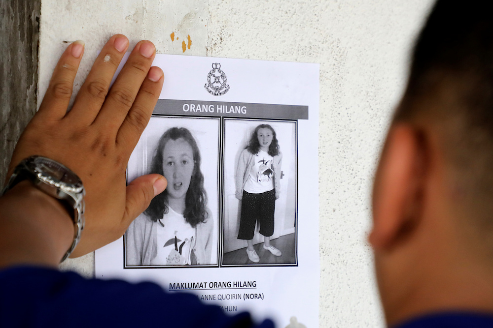 A police officer pastes a photo of 15-year-old Irish girl Nora Anne Quoirin who went missing from a resort on a wall at a shop in Seremban August 9, 2019. u00e2u20acu201d Reuters pic