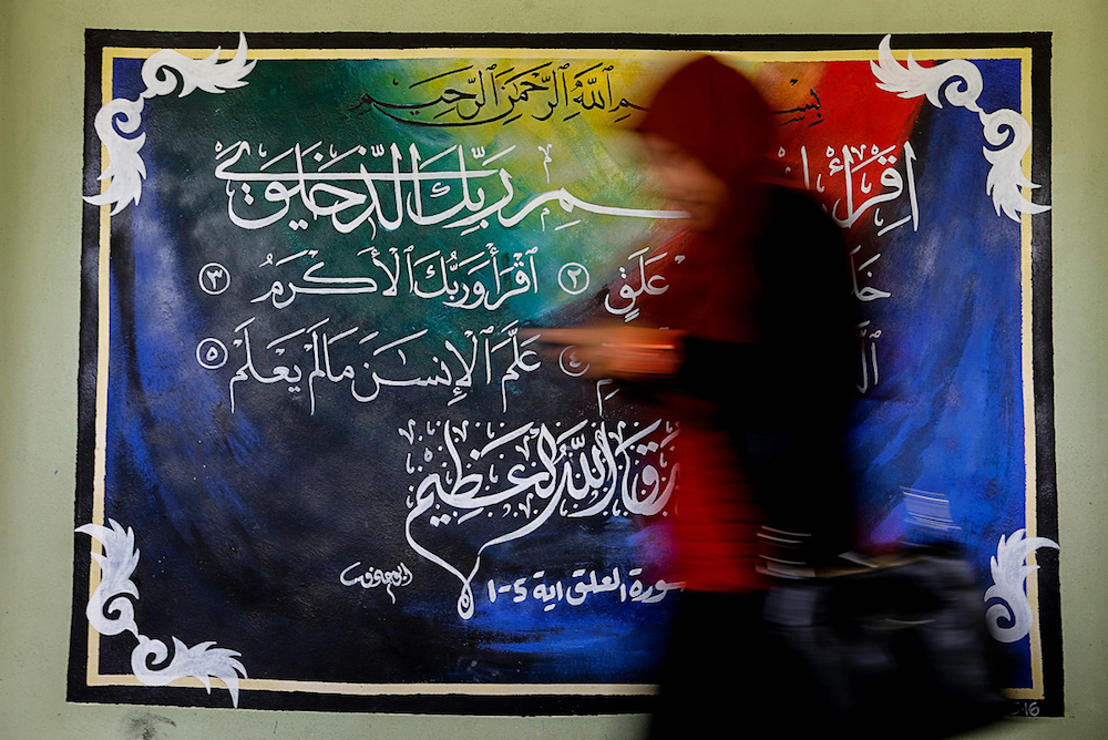 A woman walks past a piece of khat calligraphy in Balik Pulau, Penang August 6, 2019. u00e2u20acu201d Picture by Sayuti Zainudin