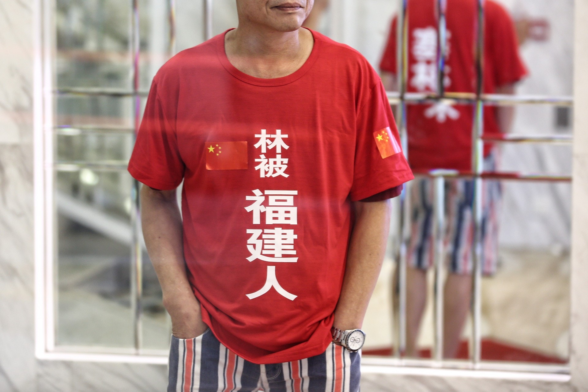红衣男子的左面肩膊亦印有中国国徽。-图取自香港01-