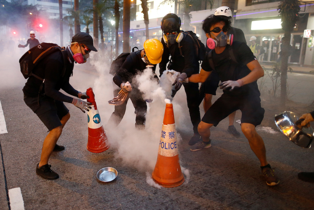 Anti-extradition bill protesters try to extinguish tear gas canisters during a demonstration in Wan Chai neighbourhood in Hong Kong August 11, 2019. u00e2u20acu201d Reuters picnn