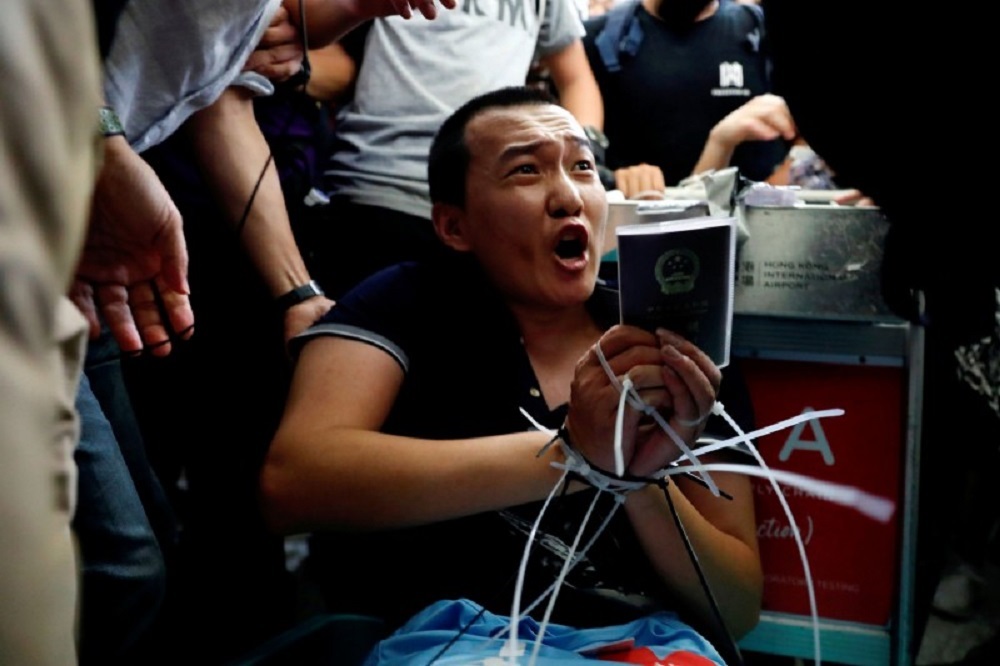 中国《环球时报》记者付国豪疑混入抗议群众被发现，遭绑在行李车上。-路透社-