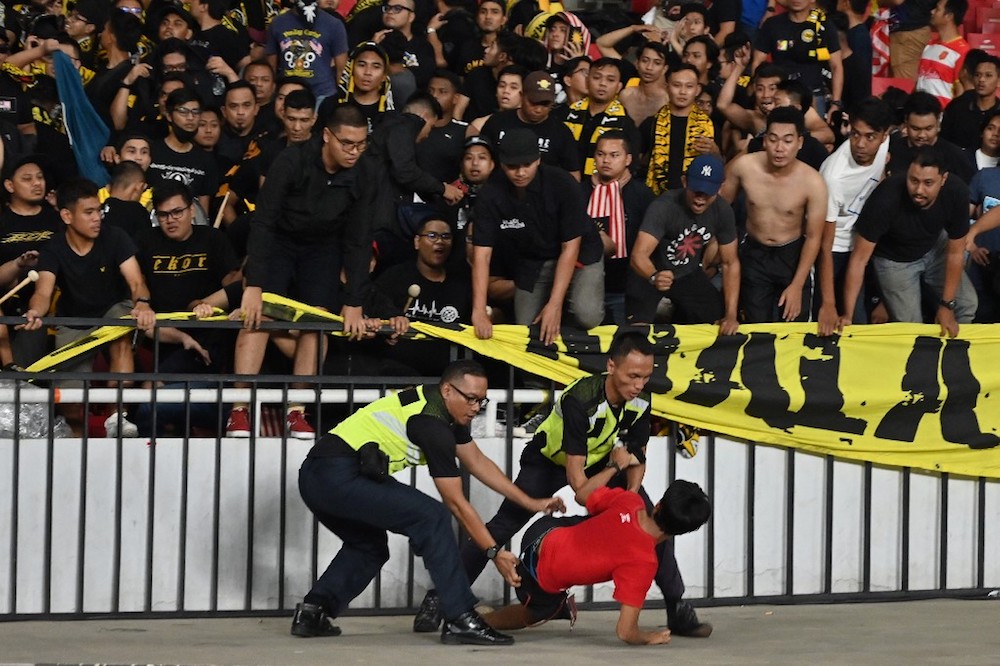 Police detain a supporter of Indonesia next to supporters of Malaysia (in black) after an incident during the Fifa World Cup preliminary qualification round 2 at Gelora Bung Karno stadium in Jakarta September 5, 2019. u00e2u20acu201d AFP pic