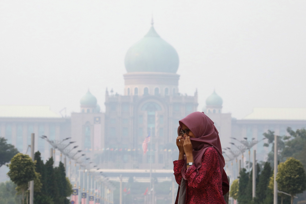 A woman covers her face with a scarf in front of the Prime Ministeru00e2u20acu2122s Office, which is shrouded in haze, in Putrajaya September 17, 2019. u00e2u20acu201d Reuters pic