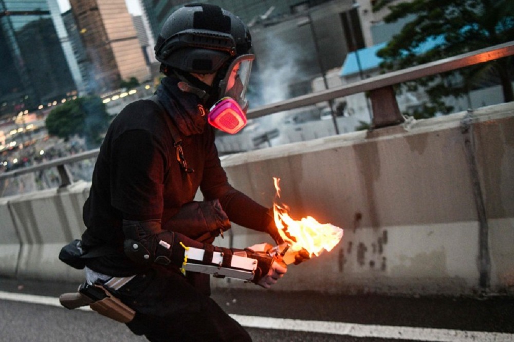法新社记者拍到一名“示威者”丢掷汽油弹的照片，有香港网民怀疑其腰际的配枪是港警常用的“Glock 19”。-法新社-