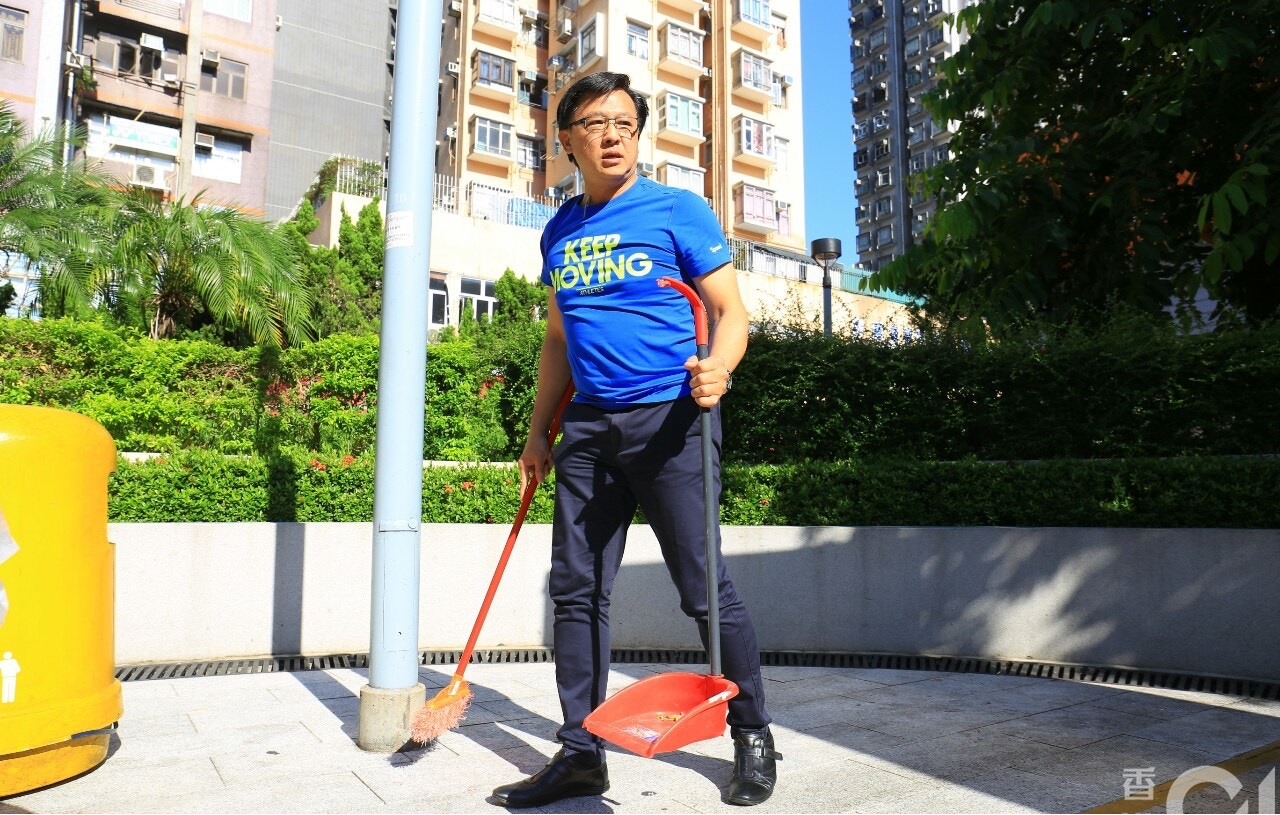 身穿蓝色上衣的何君尧周六早上手持扫把，亲自在屯门公园内扫地。-图取自香港01-