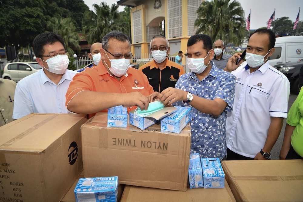 Johor Education, Human Resource, Science and Technology Committee chairman Aminolhuda Hassan examines some of the 50,000 face masks that will be distributed to schools in Tangkak and Muar, in Tangkak September 14, 2019. u00e2u20acu201d Bernama pic