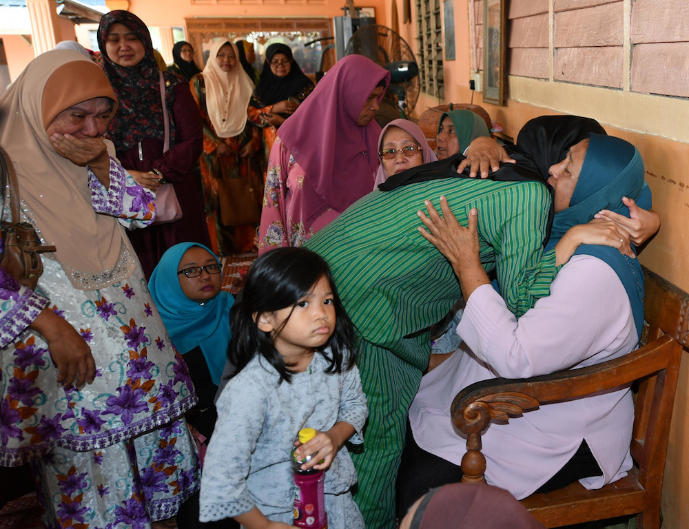 Datuk Dr Md Farid Md Rafiku00e2u20acu2122s widow, Datin Farah Syazani Hanis Ismail (in green), embraces her mother-in-law Norma Mohamed in Kampung Serkat Laut, Pontian September 21, 2019. u00e2u20acu201d Bernama pic