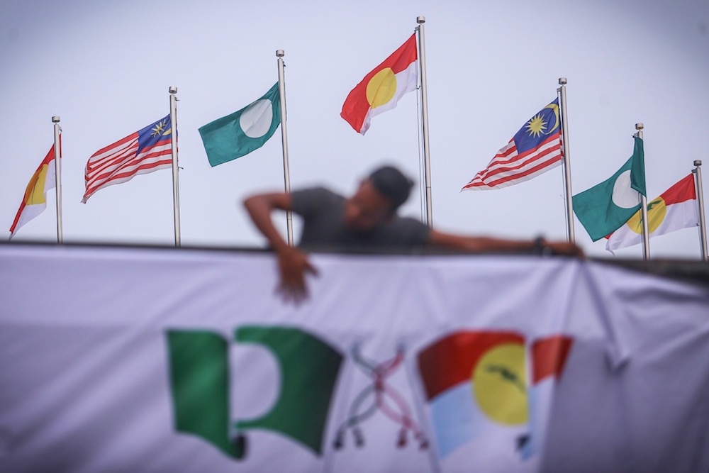 A man hangs Umno, PAS and Malaysia flags at Putra World Trade Centre in Kuala Lumpur September 12, 2019, ahead of the Muslim Unity Rally. u00e2u20acu201d Picture by Hari Anggara