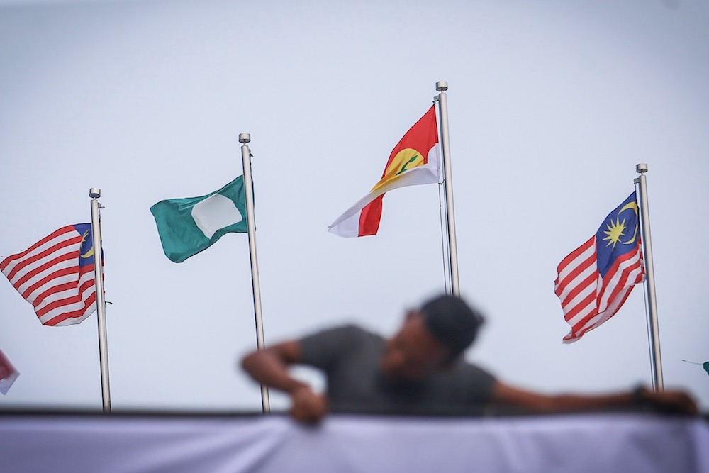A man hangs Umno, PAS and Malaysia flags at Putra World Trade Centre in Kuala Lumpur September 12, 2019, ahead of the Muslim Unity Rally. u00e2u20acu201d Picture by Hari Anggara