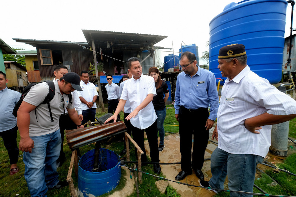 Sabah Water Department director Amarjit Singh (2nd right) looks on as Sabah Infrastructure Development Minister Datuk Peter Anthony (centre) examines a well in Kampung Pulau Berhala, Sandakan October 2, 2019. u00e2u20acu201d Bernama pic