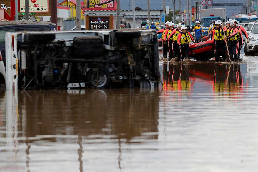 Rescue workers carry a rubber dinghy past an overturned car as they search a flooded area in the aftermath of Typhoon Hagibis in Nagano Prefecture, Japan October 14, 2019. u00e2u20acu201d Reuters pic