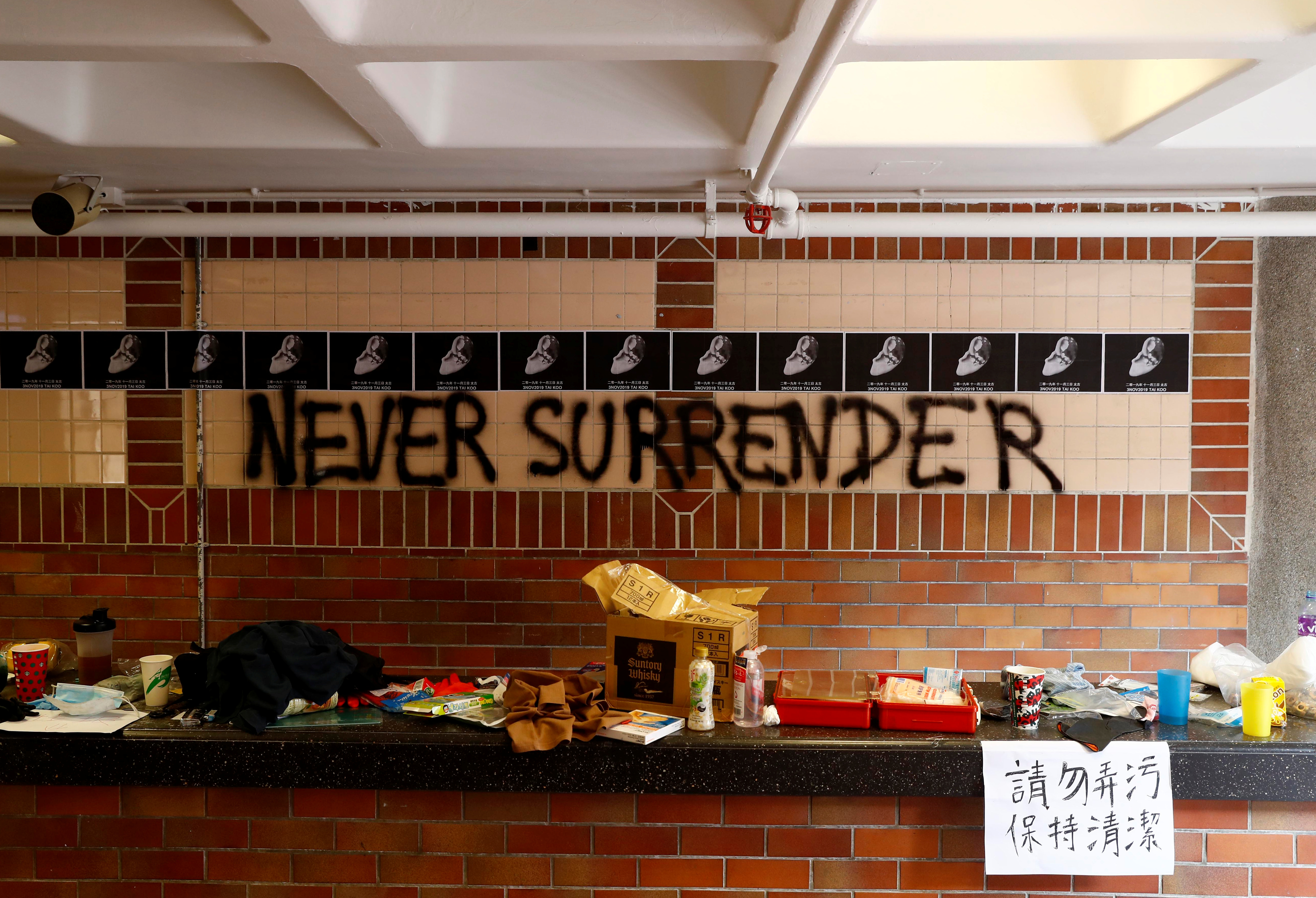 烽烟过后，理大校园一片狼藉。墙上涂鸦写着“永不投降”。-路透社-