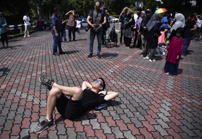 这位名叫Matthias Tan Meng Yee的游客不畏烈阳，直接戴上特殊眼镜躺在地上全程“追踪”日环食现象。-马新社-