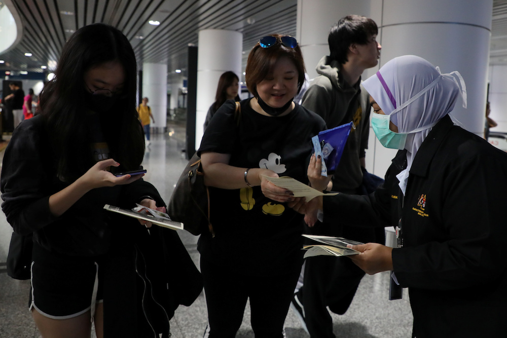 A Malaysian health quarantine officer distributes leaflets about the Wuhan Pneumonia to passengers at Kuala Lumpur International Airport in Sepang January 21, 2020. u00e2u20acu201d Reuters pic