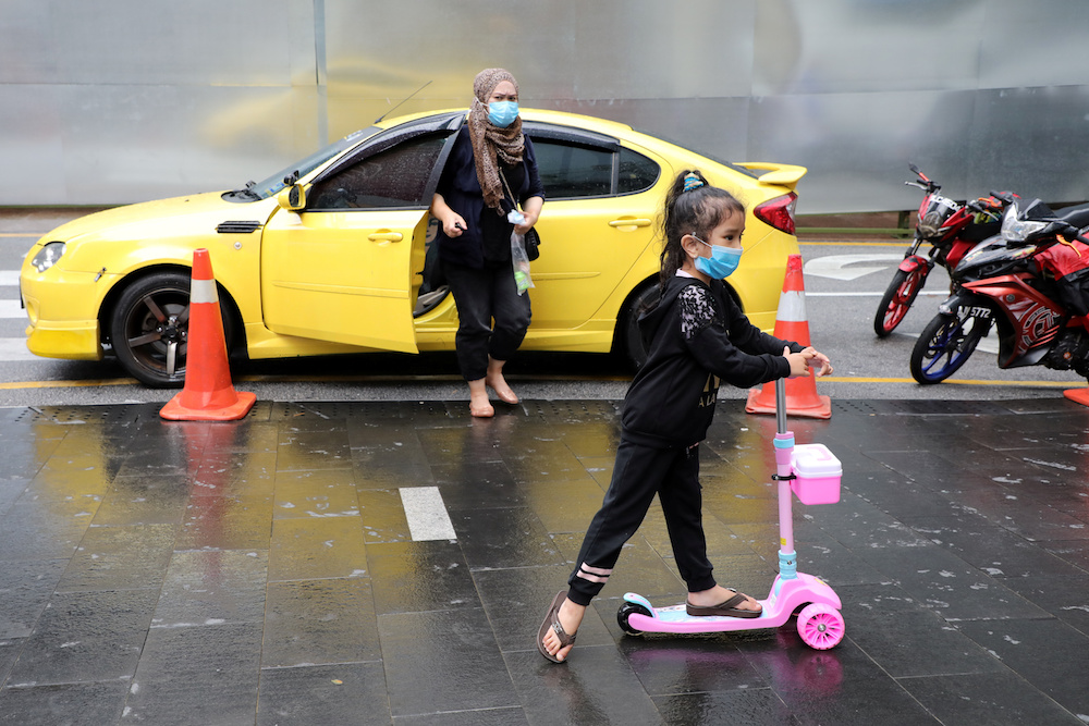 A girl wearing a mask plays with a scooter outside a shopping mall in Kuala Lumpur January 29, 2020. u00e2u20acu201d Reuters pic