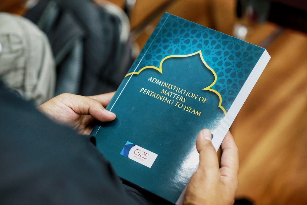 A man holds a copy of G25u00e2u20acu2122s u00e2u20acu02dcAdministration of Matters Pertaining to Islamu00e2u20acu2122 report in Kuala Lumpur January 11, 2020. u00e2u20acu201d Picture by Ahmad Zamzahuri