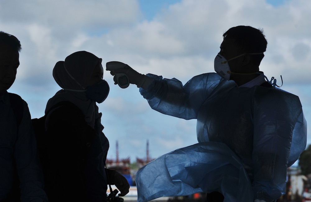 A health worker takes the temperature of a tourist at the Labuan International Ferry Terminal January 30, 2020. u00e2u20acu201d Bernama pic