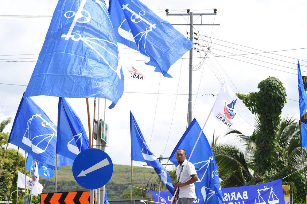A man holds a Warisan flag in front of a sea of Barisan Nasional flags in Membakut January 5, 2020, ahead of the Kimanis by-election on January 18. u00e2u20acu201d Bernama pic