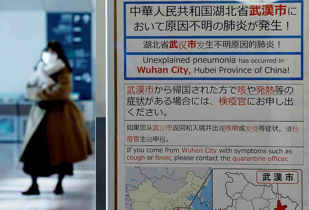 A woman wearing a mask walks past a quarantine notice about the outbreak of coronavirus in Wuhan, China at an arrival hall of Haneda airport in Tokyo January 20, 2020. u00e2u20acu201d Reuters pic 
