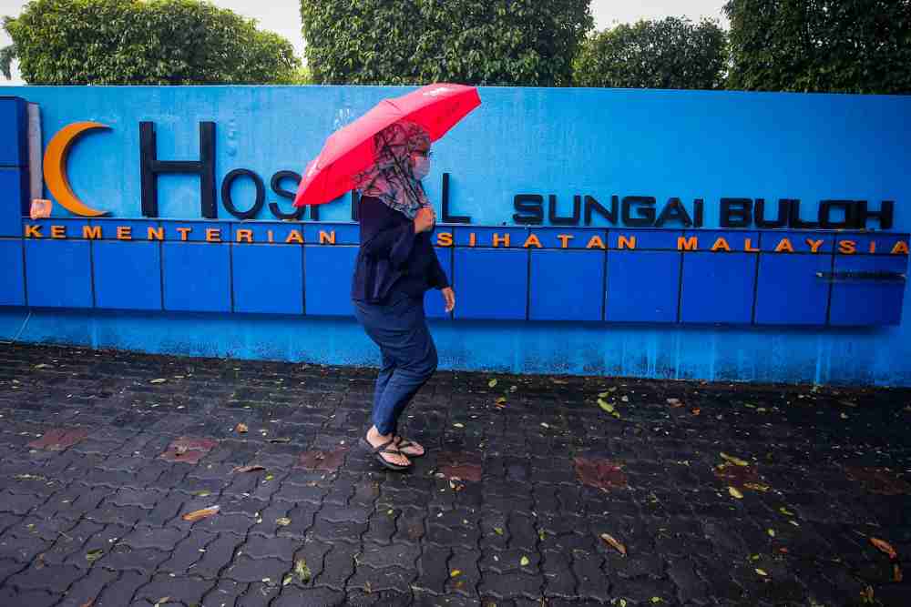 A woman with a face mask walks past the main gate of Sungai Buloh Hospital January 29, 2020. u00e2u20acu201d Picture by Hari Anggara