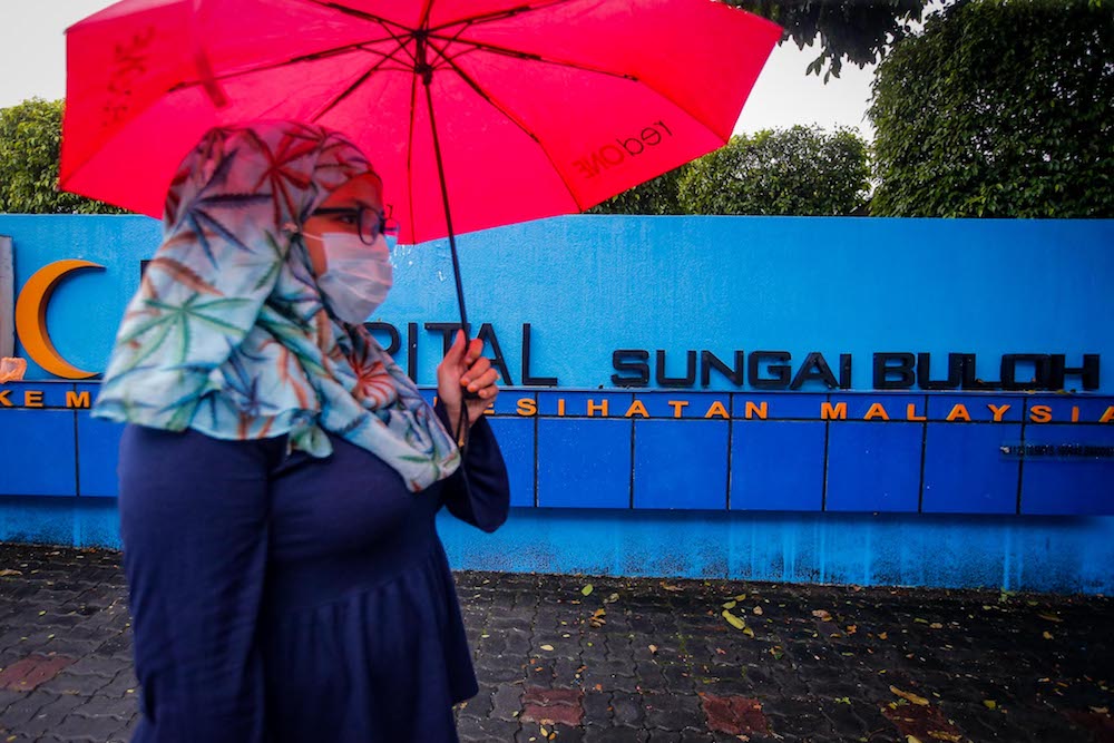A woman with a face mask walks past the main gate of Sungai Buloh Hospital January 29, 2020. u00e2u20acu201d Picture by Hari Anggara
