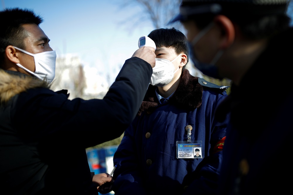 A staff member uses a thermometer to check the temperature of a colleague at an entrance of a residential complex, as the country is hit by an outbreak of the new coronavirus, in Beijing February 1, 2020. u00e2u20acu201d Reuters pic