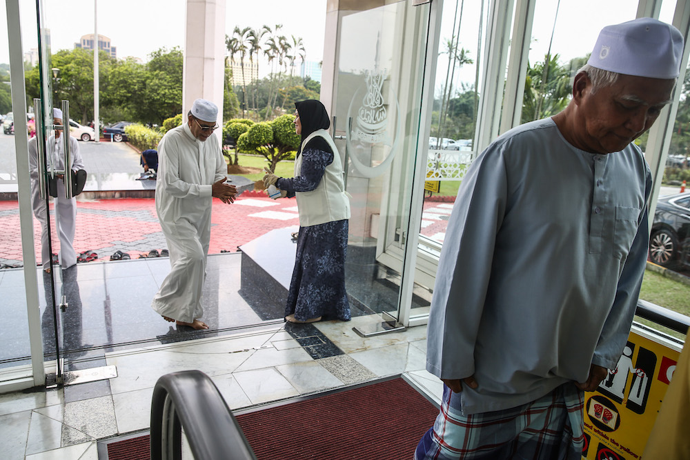 Staff member from mosque distributes hand sanitiser to worshippers during Friday prayers at Sultan Salahuddin Abdul Aziz Shah Mosque in Shah Alam March 13, 2020. u00e2u20acu201d Picture by Yusof Mat Isa