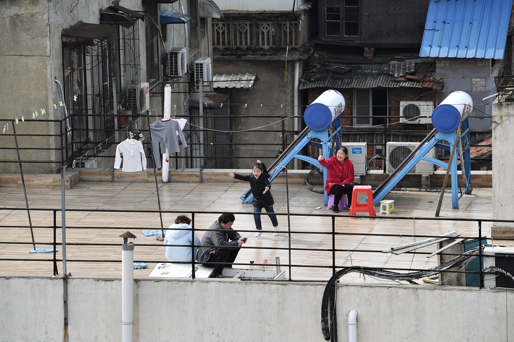 A child plays next to adults sitting on the roof terrace of a building at a residential compound in Wuhan March 4, 2020. u00e2u20acu201d Reuters pic