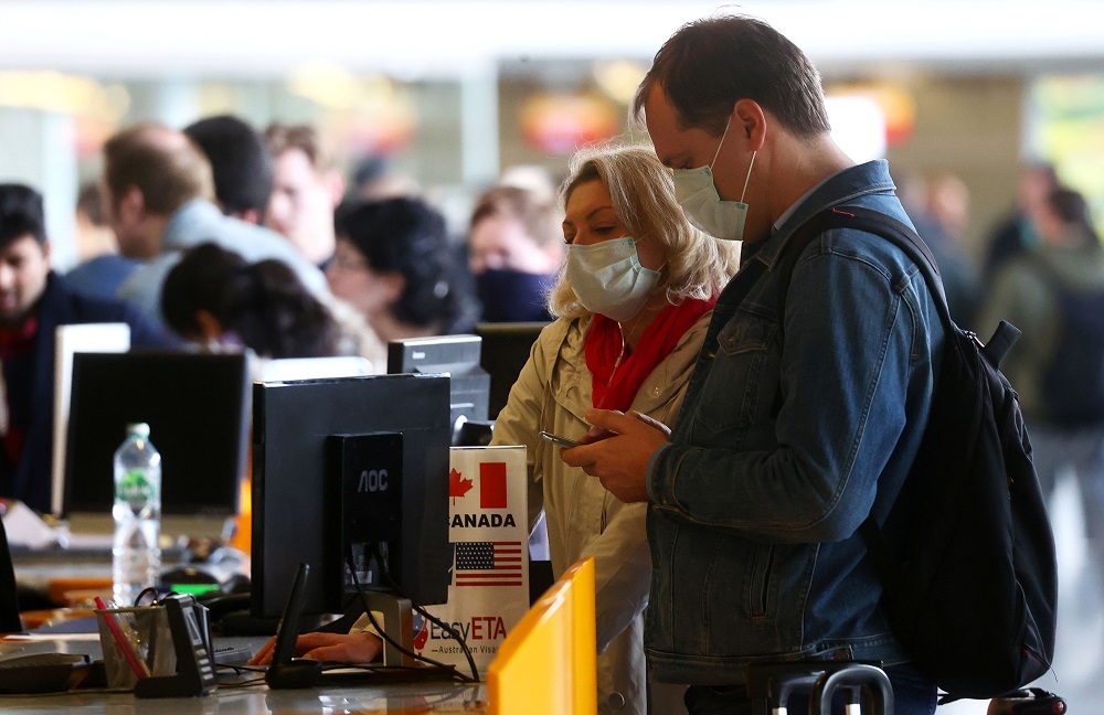 Passengers wear protective masks against the coronavirus disease as they wait at a ticket counter at the airport in Frankfurt March 13, 2020. u00e2u20acu201d Reuters pic