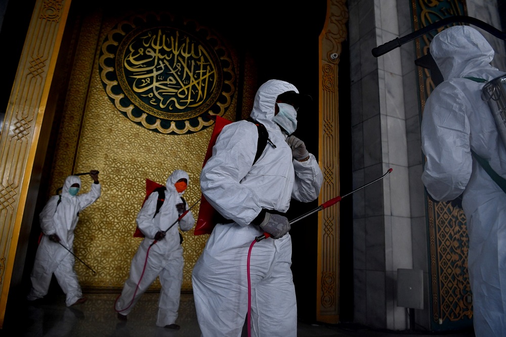 Officers of Local Disaster Mitigation Agency in protective suits carry disinfectant spray at a mosque amid the spread of coronavirus disease in Surabaya, East Java province March 17, 2020. u00e2u20acu201d Picture by Antara Foto via Reuters