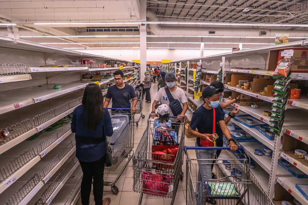People walk by near empty shelves are seen at Tesco Ampang, amid panic buying following the restriction of movement order announced by the government, in Kuala Lumpur March 17, 2020. u00e2u20acu201d Picture by Firdaus Latif