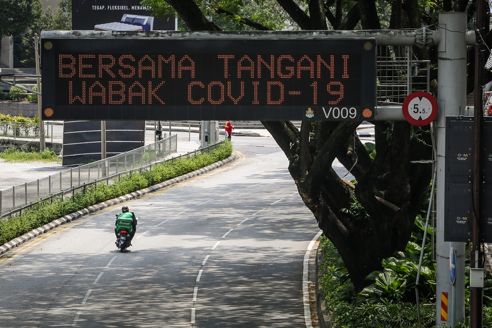 A motorist rides past a giant LED screen urging the public to cooperate in the fight against the Covid-19 outbreak, at Jalan Ampang in Kuala Lumpur March 21, 2020. u00e2u20acu201dPicture by Yusof Mat Isa