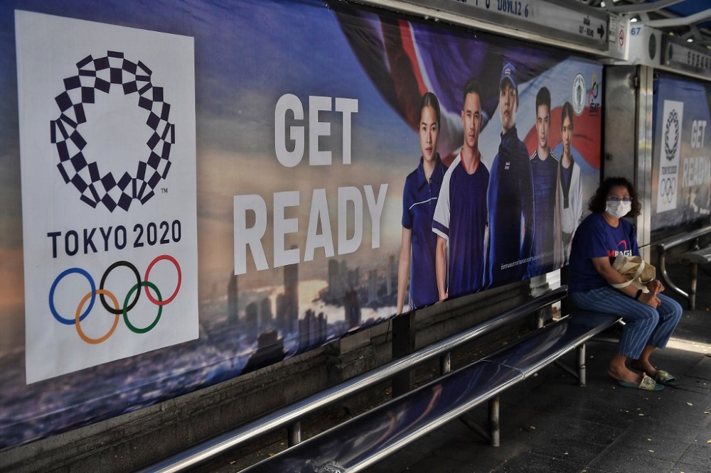 A woman wears a face mask amid concerns over the spread of the Covid-19 coronavirus as she sits at a bus stop advertising the Tokyo 2020 Summer Olympics in Bangkok March 20, 2020. u00e2u20acu201d AFP pic