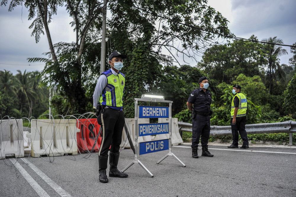 Police officers conducting checks at a roadblock during the enhanced movement control order (EMCO) in seven villages in Hulu Langat, March 30, 2020. u00e2u20acu201d Picture by Shafwan Zaidon