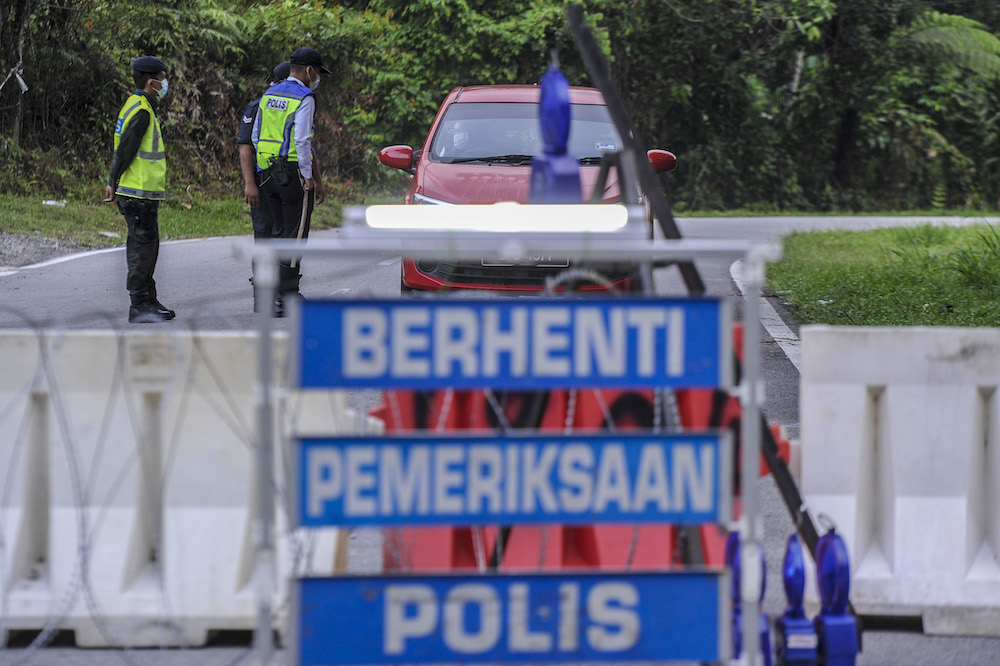 Police officers conducting checks at a roadblock during the enhanced movement control order (EMCO) in seven villages in Hulu Langat, March 30, 2020. u00e2u20acu201d Picture by Shafwan Zaidon