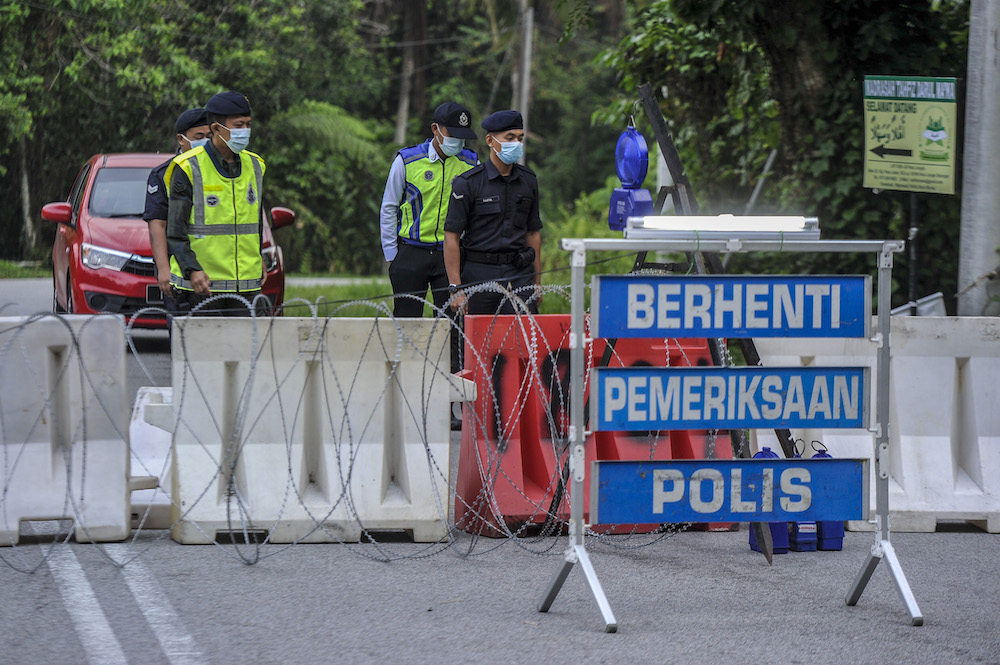 Police officers conducting checks at a roadblock during the enhanced movement control order (EMCO) in seven villages in Hulu Langat, March 30, 2020. u00e2u20acu201d Picture by Shafwan Zaidon