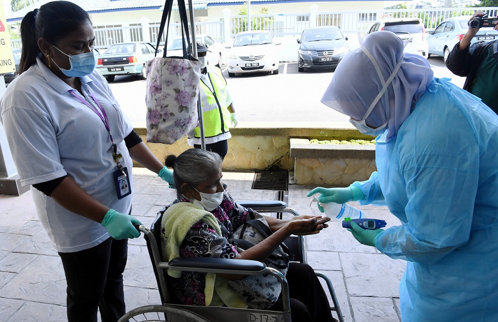 A health worker at Mawar Medical Centre provides hand sanitiser to a wheelchair-bound elderly woman in Seremban March 20, 2020. u00e2u20acu201d Bernama pic