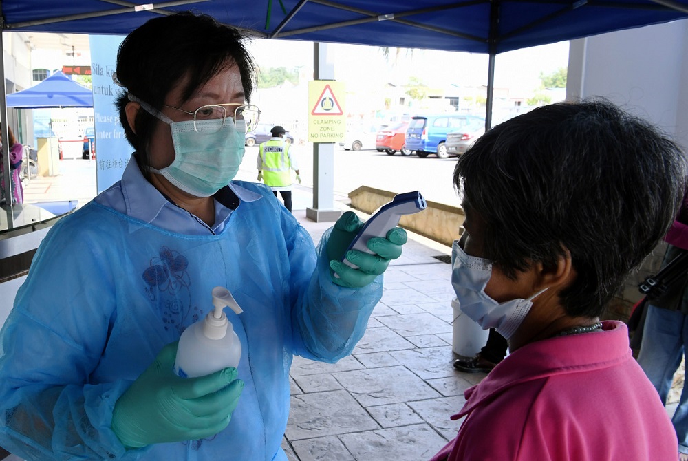 A health worker from Mawar Medical Centre checks the temperature of a visitor in Seremban March 20, 2020. u00e2u20acu201d Bernama pic