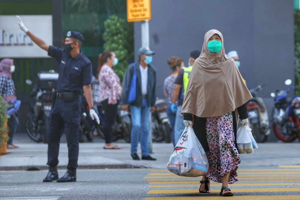 A shopper makes her way out of the Chow Kit wet market with her groceries in Kuala Lumpur March 27, 2020. u00e2u20acu2022 Picture by Ahmad Zamzahuri
