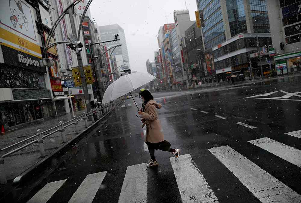 A woman wearing a protective face mask walks past on a nearly empty street in a snow fall at an shopping and amusement district in Tokyo, Japan March 29, 2020. u00e2u20acu201d Reuters pic