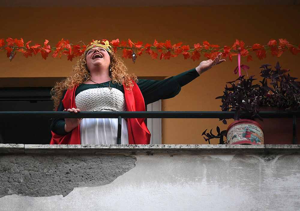 A woman sings from her balcony as the Italian government continues restrictive movement measures to combat the coronavirus outbreak, in Rome Italy March 14, 2020. u00e2u20acu201d Reuters pic