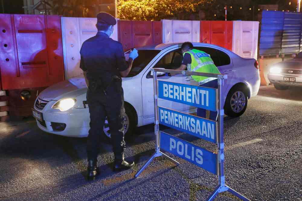 Police officers inspect a vehicle during a roadblock in Kepong March 19, 2020. u00e2u20acu2022 Picture by Ahmad Zamzahuri