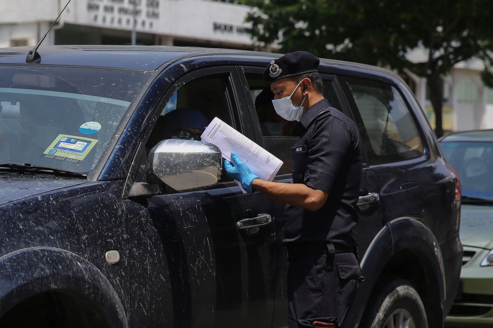 A police personnel conducts checks on a vehicle during a roadblock in Kuala Lumpur March 31, 2020. u00e2u20acu201d Picture by Yusof Mat Isa
