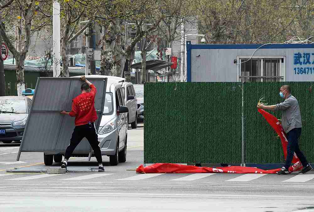 Workers wearing face masks remove barriers on a street in Wuhan as the city has started to loosen its Covid-19 lockdown, in Hubei province, China March 21, 2020. u00e2u20acu201d China Daily pic via Reuters 