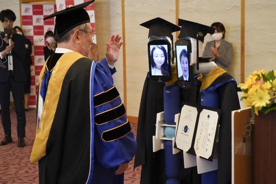毕业生的脸会显示在“newme”机器人的显示屏上，从校长手中“领取”毕业证书。-图片摘自网络-