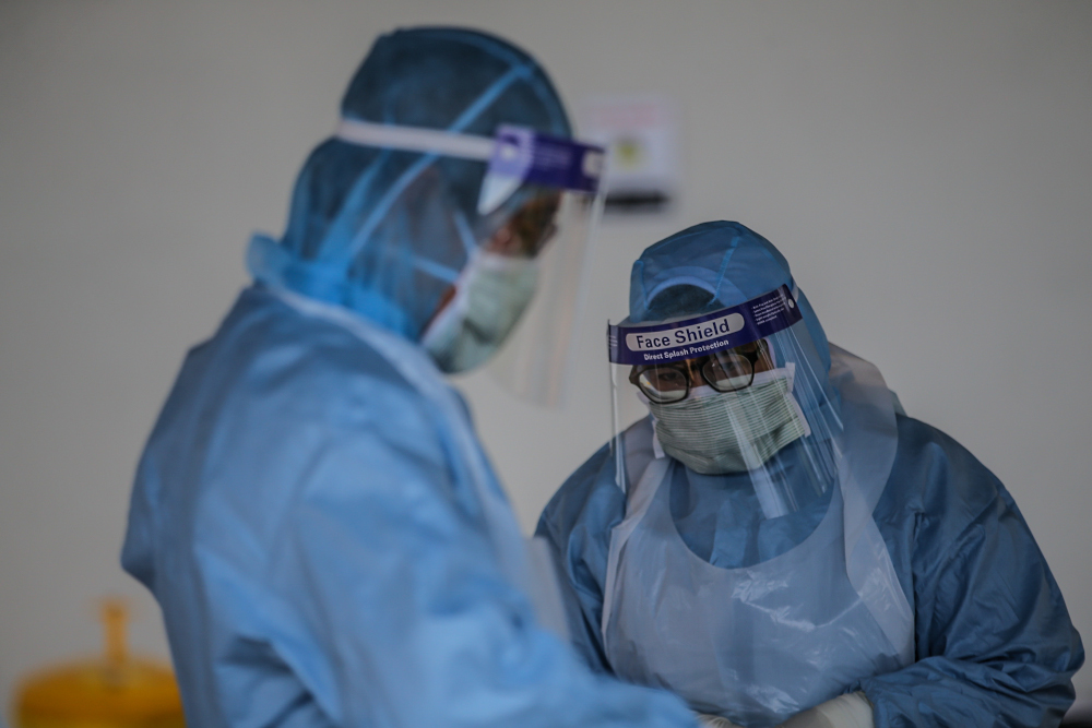 A medical worker takes a swab at a Covid-19 drive-through screening area at KPJ Ampang Puteri April 9, 2020. u00e2u20acu201d Picture by Hari Anggara