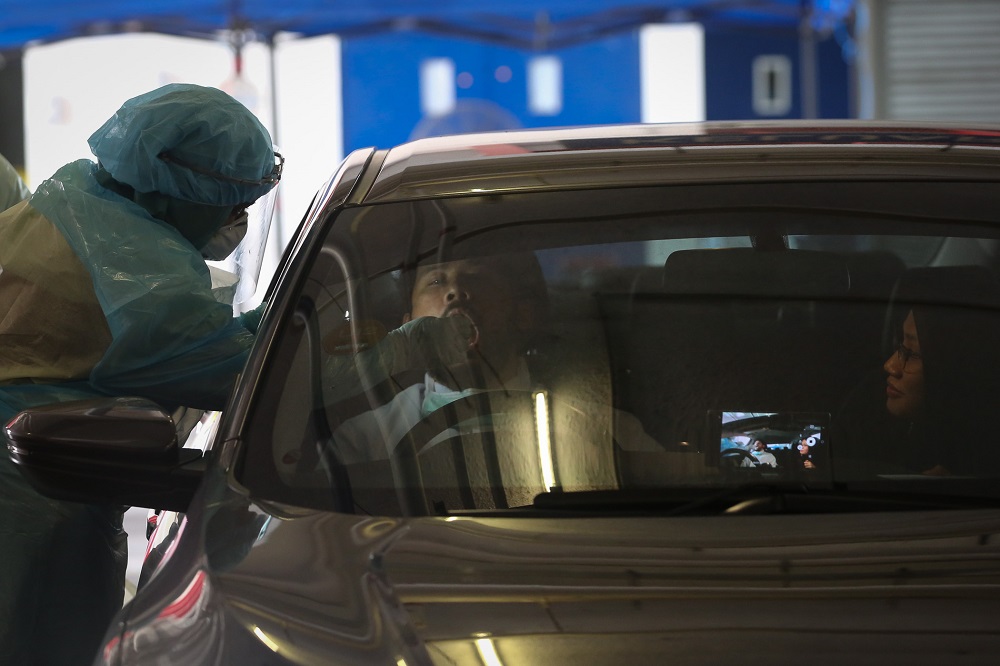 A health worker in protective suit collects swab samples from a motorist at a drive-through testing site for Covid-19 at MSU Medical Centre in Shah Alam April 10, 2020. u00e2u20acu201d  Picture by Yusof Mat Isa