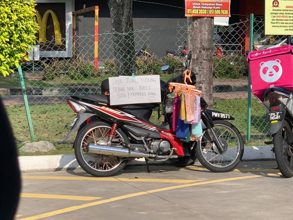 The man was seen at Petronas Seberang Jaya selling head shawls so he could buy milk and diapers for his kids. u00e2u20acu201d Photo courtesy of Facebook/ Alin Taharin