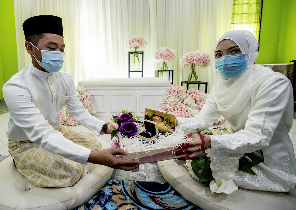 Abdul Khalib Abdullah, 27, menyampaikan mas kahwin kepada isterinya Nurul Fatihah Mat Husin, 27, selepas selesai akad nikah di Kampung Bukit, Pasir Puteh hari ini. u00e2u20acu201d Foto Bernamann
